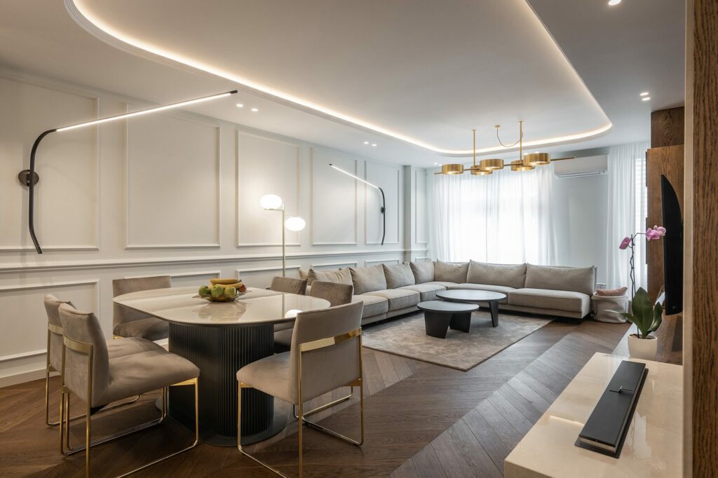 dark hardwood flooring in contemporary living and dining room with modern lighting neutral furniture and area rug