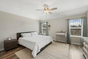 light hardwood flooring in bright bedroom with neutral area rug large windows and minimalist decor