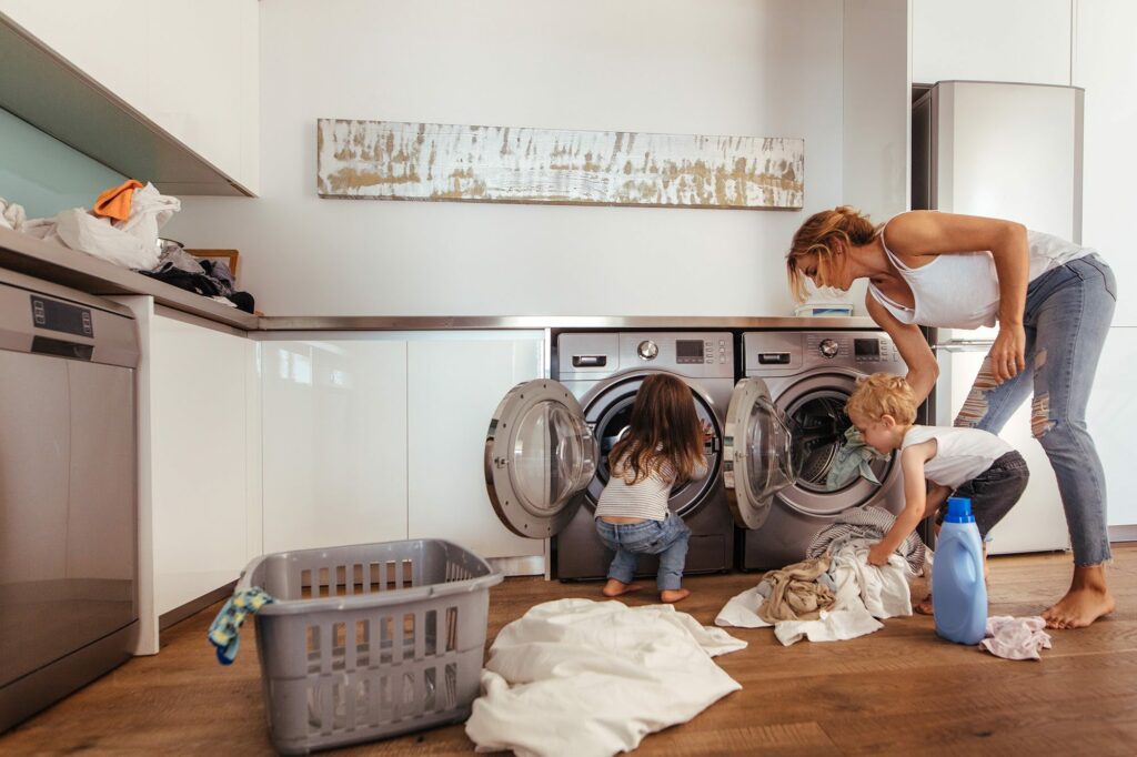 family doing laundry on waterproof luxury vinyl flooring in contemporary utility room with front load washers